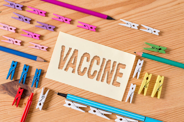 Handwriting text Vaccine. Concept meaning preparation of killed microorganisms or living attenuated organisms Colored clothespin papers empty reminder wooden floor background office. - Photo, Image