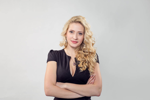 Happy and successful. Portrait of a happy beautiful smiling girl woman standing with arms folded. Caucasian Business person in black formal dress, long blond curly hair isolated on light grey gray - Fotoğraf, Görsel