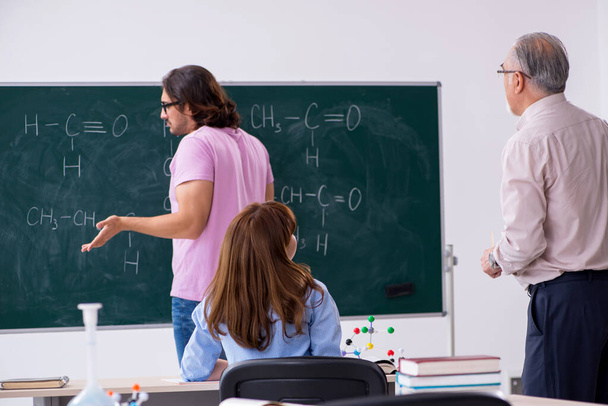 Régi kémikus tanár és két diák az osztályteremben. - Fotó, kép