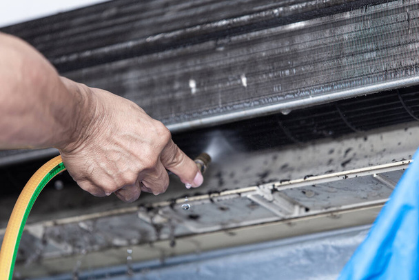 Male technician cleaning dirty air conditioner. - 写真・画像