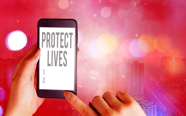 Word writing text Protect Lives. Business concept for to cover or shield from exposure injury damage or destruction Modern gadgets with white display screen under colorful bokeh background. - Photo, Image