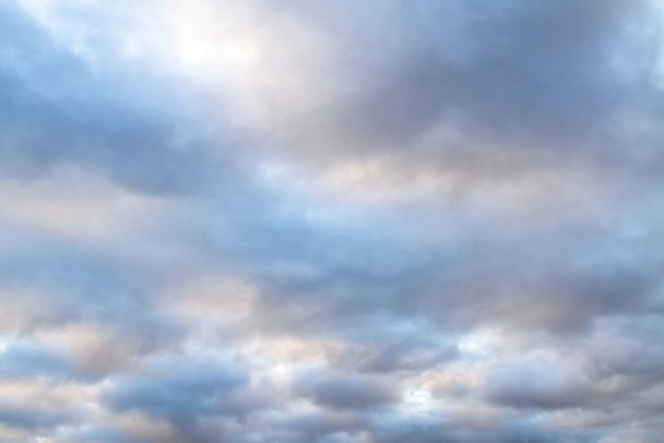 Prachtige lucht op een bewolkte dag met blauwe en paarse tinten op cumulus hemel wolken. Bewolkt weer in de herfst avond. Helder wolkenlandschap met witte zonnevlekken, passerend door de pluizige wolken. - Foto, afbeelding