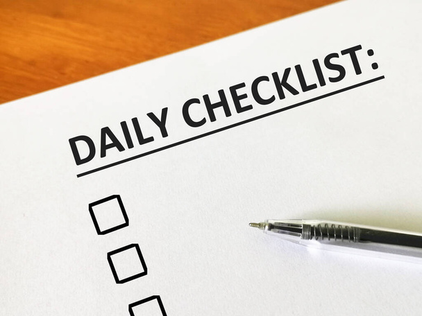 Один человек пишет свой ежедневный контрольный список, чтобы помочь ему завершить свою работу более эффективно. - Фото, изображение