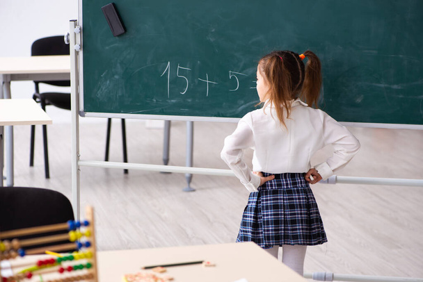 Petite fille devant le tableau noir dans la salle de classe - Photo, image