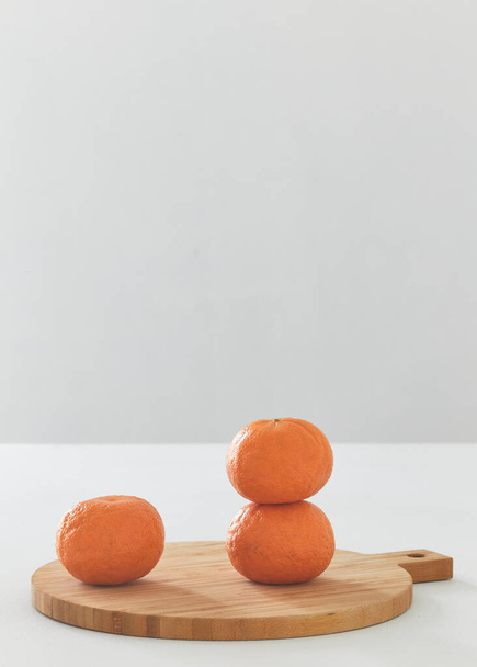 Помаранчеві фрукти на обробній дошці на білому столі
 - Фото, зображення