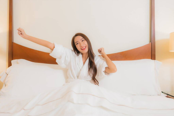 retrato hermosa joven asiática mujer sonrisa relajarse ocio en cama en dormitorio interior - Foto, imagen