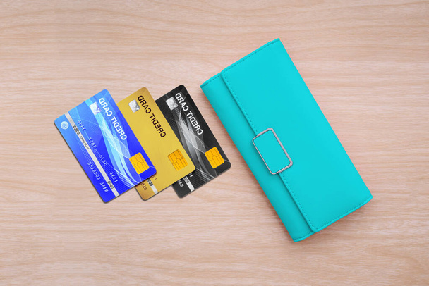 Вид зверху на гаманець і кредитні картки на фоні дерев'яного столу
. - Фото, зображення