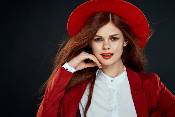 mooie vrouw met rode lippen hoed op haar hoofd jas elegante stijl charme donker geïsoleerde achtergrond - Foto, afbeelding