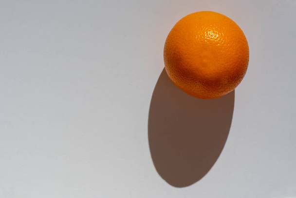 Naranja jugosa fresca sobre un fondo blanco con una sombra dura. Vista superior. espacio de copia. - Foto, Imagen