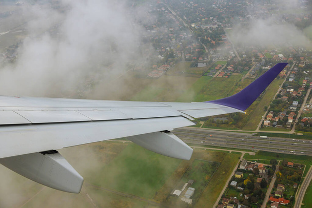 Vliegtuig in de lucht boven velden de vleugel is zichtbaar door het raam luchtvervoer. - Foto, afbeelding