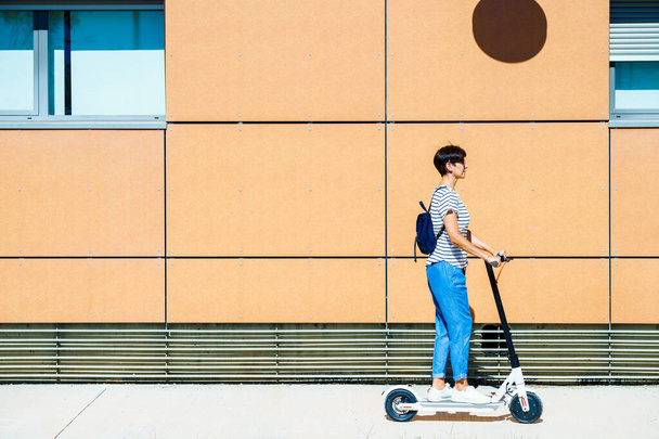 Femme chevauchant autour de la ville sur un scooter électrique - Photo, image