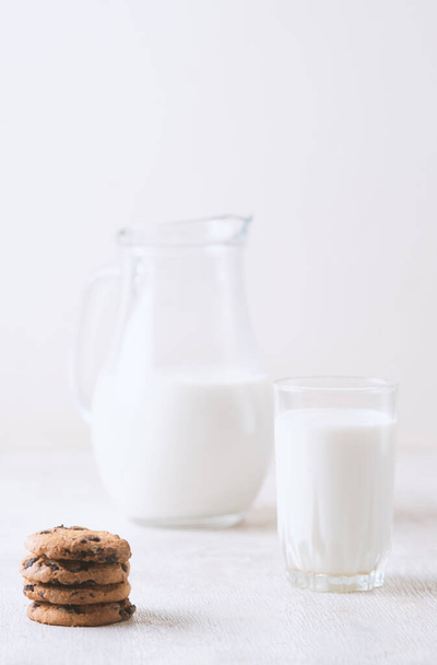Milk in a jug and chocolate chip cookies on on a white wooden background copy space. - Photo, Image