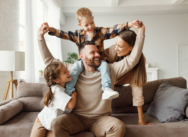 happy family mother father and kids play and laugh at home on   couch  - Fotografie, Obrázek
