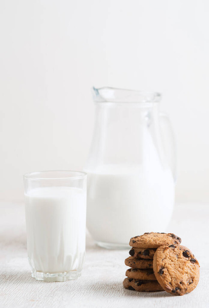 Milk in a jug and chocolate chip cookies on on a white wooden background copy space. - Fotografie, Obrázek