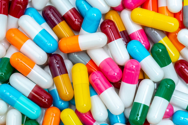Kleurrijke capsule pillen. Farmaceutische industrie. Gezondheidszorg en medische achtergrond. Farmaceutisch concept. Antibioticaresistentie. Roze, wit, oranje, rood, groen, blauw en grijs capsule pillen. - Foto, afbeelding