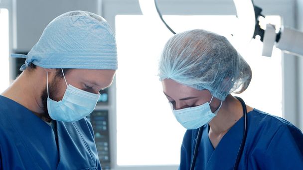 Professional medical doctors working in emergency medicine. Portrait of the surgeon and the nurse in protective masks performing surgical operation. - Valokuva, kuva