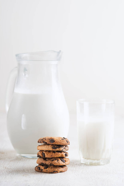 Milk in a jug and chocolate chip cookies on on a white wooden background copy space. - 写真・画像
