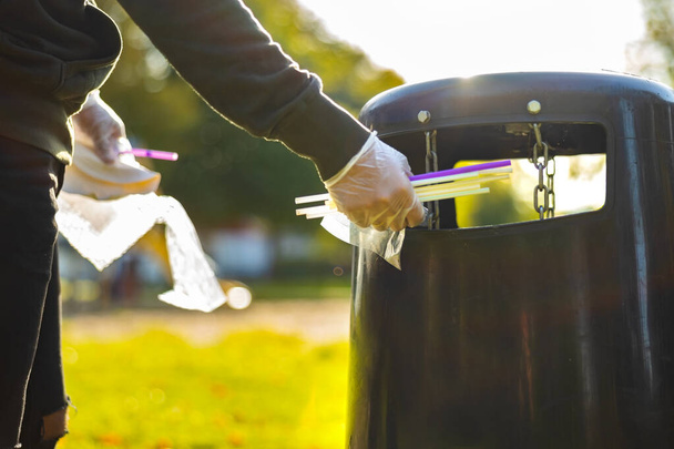 Vapaaehtoinen heittää pillit roskakoriin puistossa - Valokuva, kuva