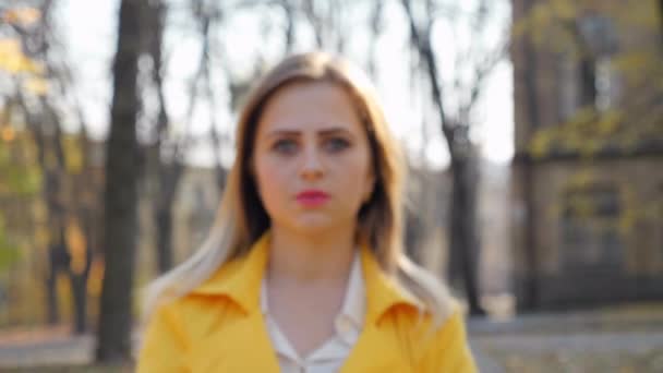 zbliżenie kobieta w płaszcz bluzka stoi wygląda kamera w park aparat porusza dziewczyna - Materiał filmowy, wideo