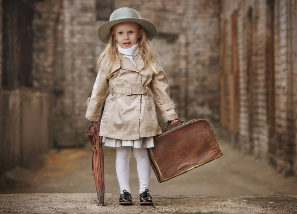 Bonne petite fille voyageant avec une vieille valise et un parapluie à ulitsme vieille ville jour d'automne - Photo, image