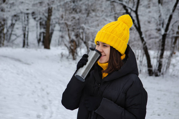 woman in winter outfit drinking warm up drink from refillable mug copy space - Photo, Image