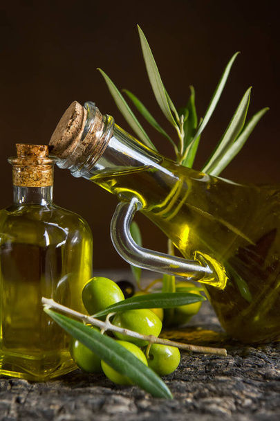 olive oil and fresh olives on the old table - Фото, изображение
