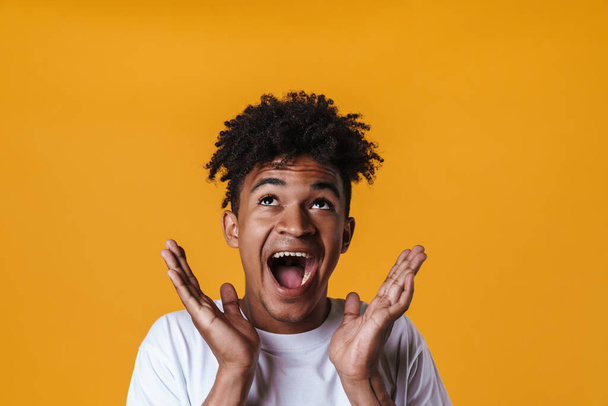 Image of excited african american guy expressing surprise on camera isolated over yellow wall - Φωτογραφία, εικόνα