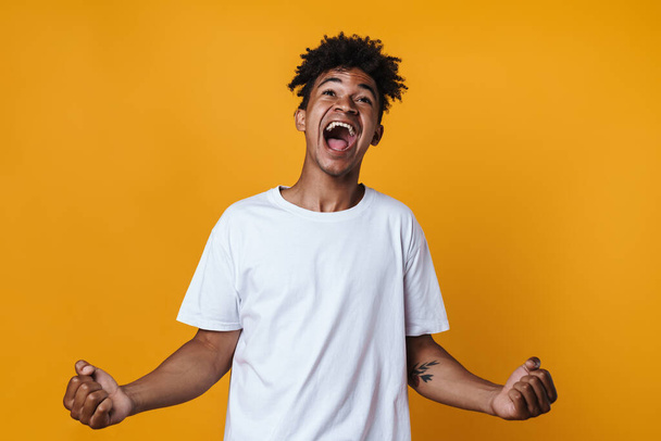 Image of excited african american guy screaming and making winner gesture isolated over yellow wall - Fotografie, Obrázek