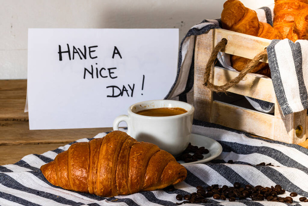 Kávé csésze és vajas friss francia croissant fából készült ládán - Fotó, kép