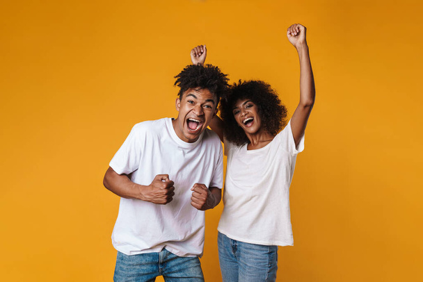 Image of excited african american couple screaming at camera isolated over yellow wall - Fotoğraf, Görsel