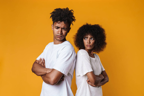 Image of resentful african american couple posing pack to back isolated over yellow wall - Foto, Imagem