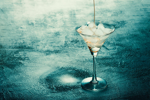 Feliz cóctel de terror de Halloween. Bebida alcohólica con hielo en una mesa de luz, pancarta. - Foto, Imagen