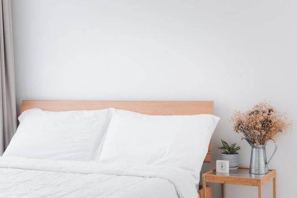 Güzel, beyaz, temiz yatak odası iç tarafı yeşil ve kurumuş saksılarla dolu tahta masa. - Fotoğraf, Görsel