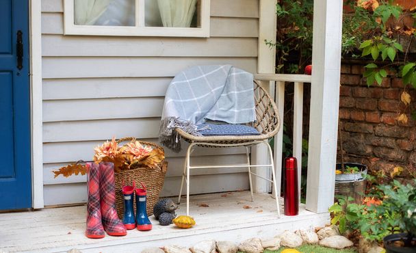 Hangulatos őszi terasz szék, kockás, gumicsizma, kosarak krizantém és tök. Díszek őszi teraszon pihenni. Stílusos őszi dekoráció a verandán. Őszi fából készült veranda otthon - Fotó, kép