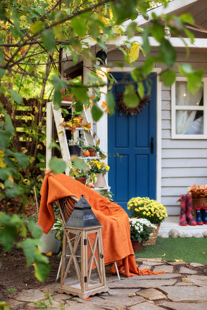 Dekorace na dvorku pro odpočinek v podzimní zahradě. Útulný podzimní terasa s židlí, kostkované, rostliny, dřevěné lucerny, v květináčích chryzantémy. Halloween. Stylový podzimní dekor na přední verandě domu. Díkůvzdání  - Fotografie, Obrázek