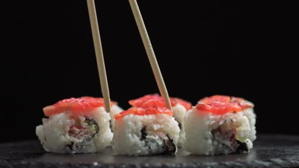 Γεύμα σε ιαπωνικό εστιατόριο. Ο άνθρωπος τρώει σούσι. Σούσι Φιλαδέλφεια από ψάρι, σολομό, ρύζι, αγγούρι. Εστιατόριο σούσι, παράδοση σούσι. Επιλεκτική εστίαση - Πλάνα, βίντεο