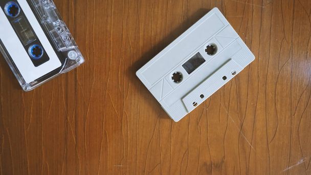 レトロな木のテーブルの上にカセットテープのクローズアップ画像。コンパクトで便利なデバイス技術で録音されたオーディオ音楽や歌のほとんどが. - 写真・画像