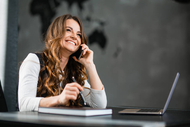 Caucasian happy girl talking on the phone in the office - Foto, Bild