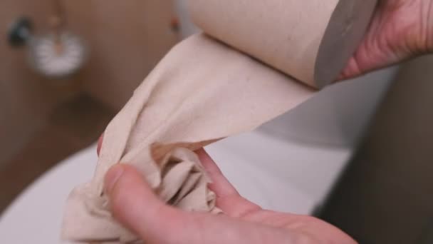 Vrouwelijke handen rollen in en scheuren een stuk toiletpapier. Een close-up. Langzame beweging - Video