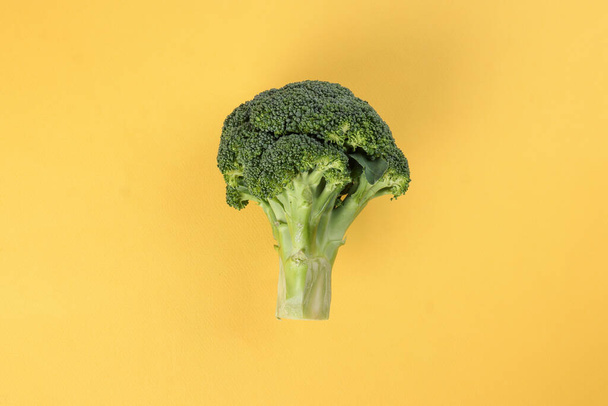 whole green broccoli closeup on yellow background - Φωτογραφία, εικόνα