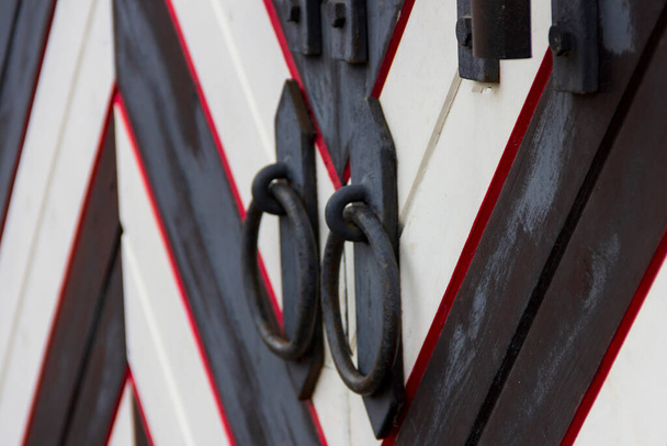 Las manijas de la puerta de hierro forjado en forma de anillo y un perno de acero cerrado con un candado en la puerta de un castillo medieval. - Foto, imagen