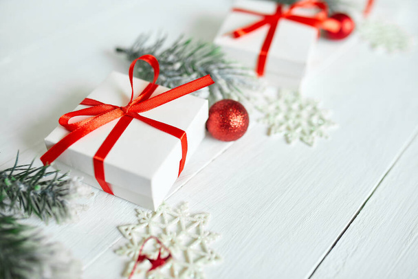 Confezione regalo di Natale, rami di abete, decorazioni rosse su sfondo bianco in legno, Natale, inverno, concetto di nuovo anno, Posa piatta, vista dall'alto, spazio copia - Foto, immagini