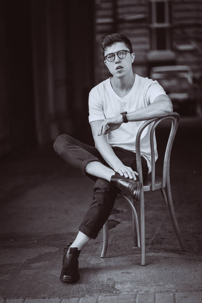 通りに白いTシャツとサングラスを身に着けて椅子に座る男性の肖像画 - 写真・画像