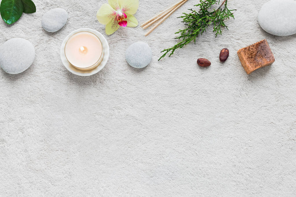 Natural Skin Care and Spa Set on white soft towel background with natural cosmetic products, flower, green leaves, candle and zen like stones. Relax concept, top view, copy space. - Foto, immagini