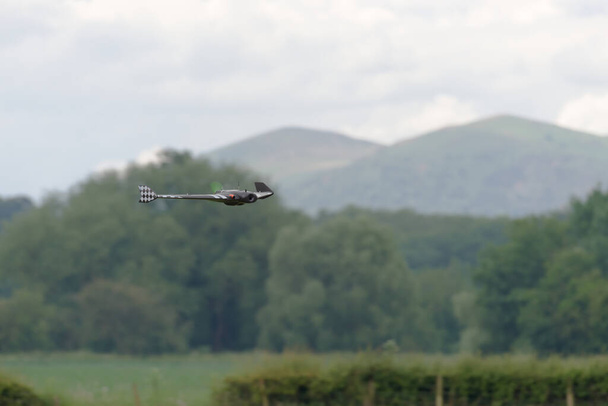 Flying low and fast in front of the malvern hills, a remote control FPV first person view flying wing is in selective focus. Propeller blurred. - Photo, Image
