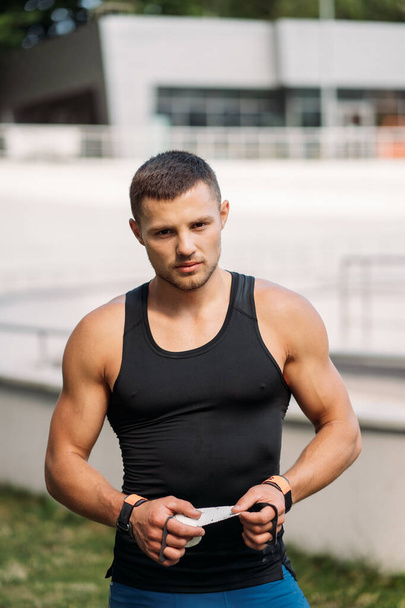 Muscular cara em shorts azuis e t-shirt preta posando ao ar livre. - Foto, Imagem