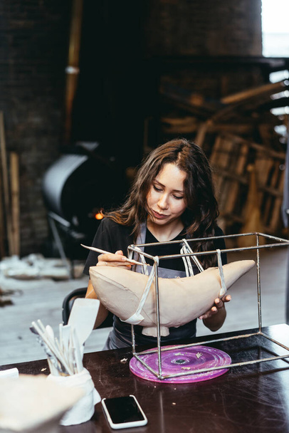 Портрет молодой женщины, наслаждающейся любимой работой в мастерской. - Фото, изображение