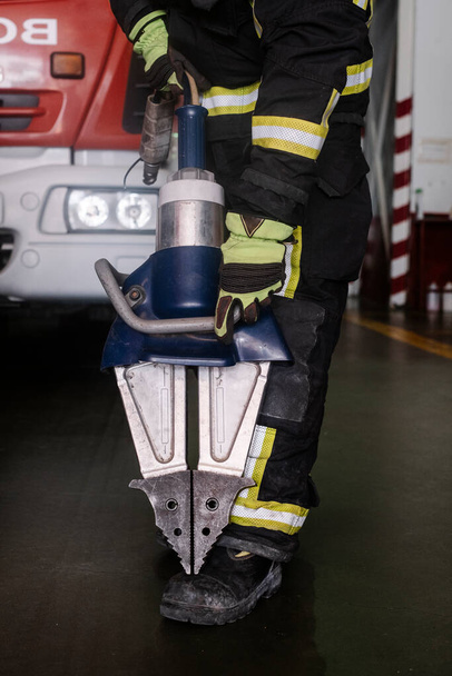 pompiere con un paio di forbici pneumatiche in una caserma dei pompieri - Foto, immagini