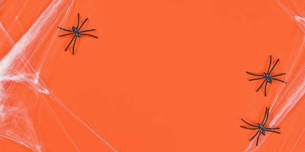 Banner with cobwebs and plastic spiders on sides of orange Halloween background with empty copy space in middle - Valokuva, kuva