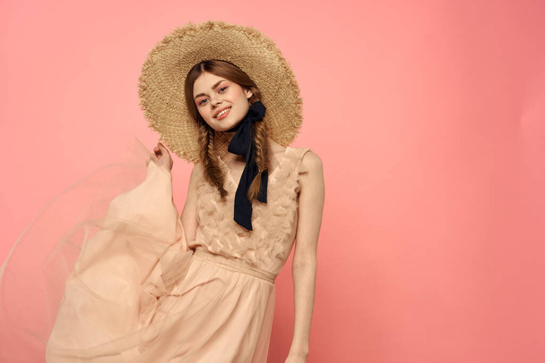 Fashionable woman in dress and hat with black ribbon on pink background cropped view of model emotions fun - 写真・画像
